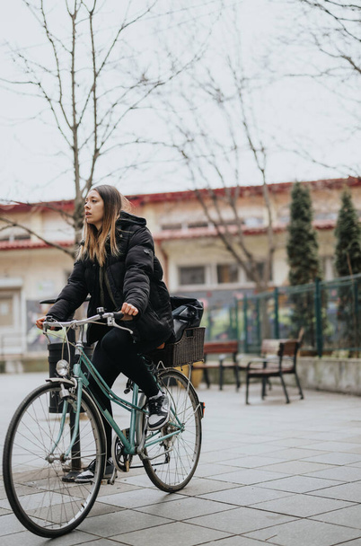 Молодая взрослая женщина на велосипеде в городской парковой среде. - Фото, изображение