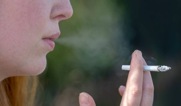 Portre, el, ağız ve el çizimi ve sigara sarılmış sigara bağımlısı genç bir kadının açık havada sigara içişini, fotokopi çekişini. - Fotoğraf, Görsel