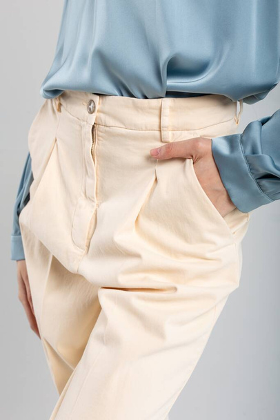 Μοντέλα μόδας σε μπεζ παντελόνι και μπλε μπλούζα με το χέρι στην τσέπη σε απομονωμένο φόντο. Κατάλληλο για διαφημίσεις μόδας. - Φωτογραφία, εικόνα