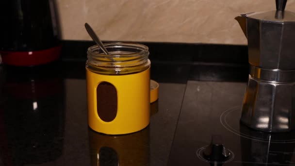 Алюминиевая винтажная кофеварка на стеклянной керамической вершине и желтая банка молотого кофе - Кадры, видео
