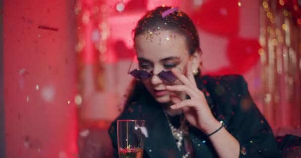 Чувственная молодая женщина в солнечных очках, пьет шампанское дома во время празднования дня галентинцев - Кадры, видео