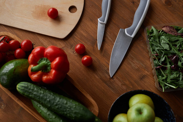 Top view cooking background with assorted fresh vegetables and steel knives on wooden table, copy space - Photo, Image