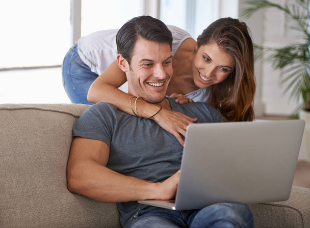 Laptop, Lächeln und Frau umarmen Mann auf Sofa Netzwerk in den sozialen Medien, Website oder Internet. Glücklich, Liebe und weibliche Person umarmen Ehemann Lesen von Online-Blog mit Computer im Wohnzimmer zu Hause - Foto, Bild