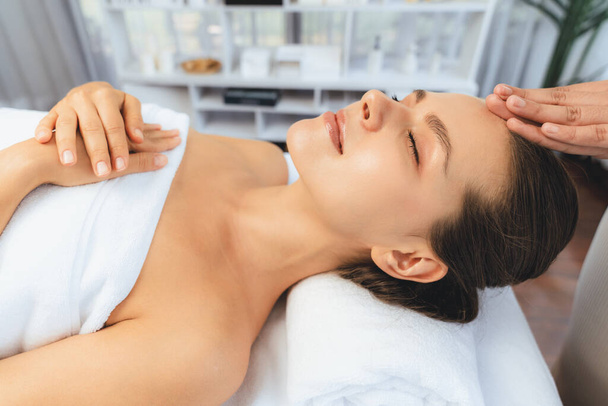 Caucasian woman enjoying relaxing anti-stress head massage and pampering facial beauty skin recreation leisure in dayspa modern light ambient at luxury resort or hotel spa salon. Quiescent - Photo, Image