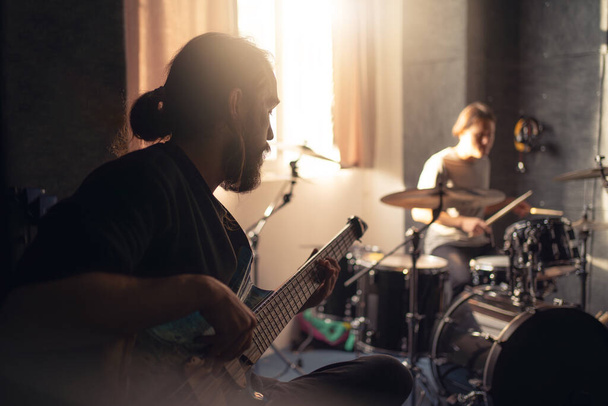 Zenekari tagok, akik egy gitárossal foglalkozó zenei stúdióban gyakorolnak.. - Fotó, kép