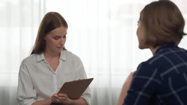 Happy patient and psychologist exchanging mental health conversation in clinic with positive emotion while explaining prim successful work and life to psychologist at psychologist clinic office - Footage, Video