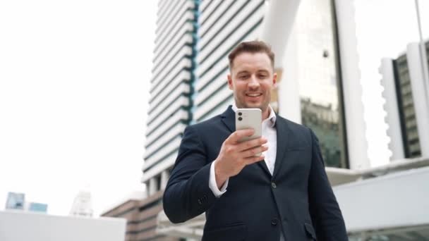 Kaukázusi üzletember ellenőrzi a mobiltelefonokat, és a marketingesek jelentéseit nézi, miközben Városi Városban áll. Képzett menedzser, aki mobilon dolgozik és adatelemzést végez. Urbane. - Felvétel, videó