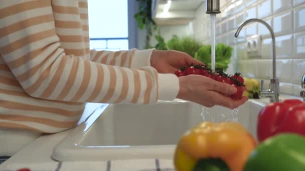 水道水の下でチェリートマトを洗う女性の手. サラダ調理に使用されるビタミンでいっぱいの健康的な有機性のおいしい新鮮な野菜. デトックス,ダイエット,エネルギーのための食品 - 映像、動画