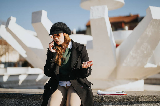 Multiculturele zakenvrouw heeft een telefoontje buiten in zonnige winter. - Foto, afbeelding