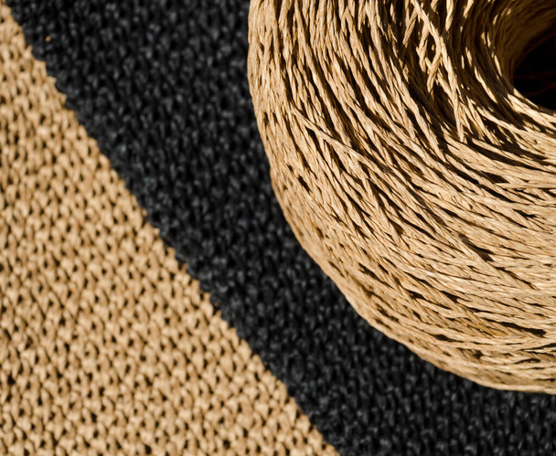 Close-up de uma meada de ráfia ECO contra um fundo de guardanapos pretos e bege. Crochê. Material ecológico para trabalho artesanal. - Foto, Imagem
