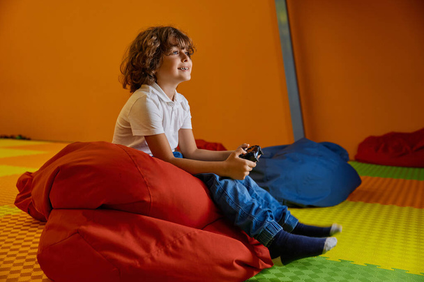 Hafta sonları eğlenirken elinde joystick ile çocuk merkezinde bilgisayar oyunu oynayan sevimli çocuk portresi. - Fotoğraf, Görsel