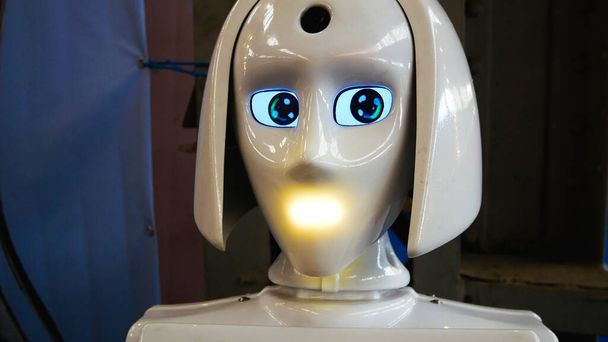 Humanoidalny robot z białego plastiku odwraca wzrok, daje sygnały świetlne i mówi. Sztuczna inteligencja. Roboty są ludzkimi asystentami.. - Zdjęcie, obraz