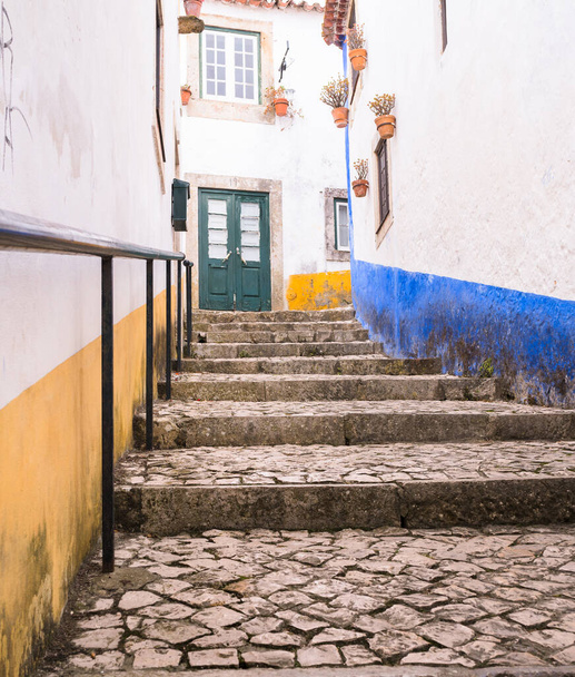 Egy régi történelmi város keskeny macskaköves utcája, lépcsőkkel felfelé.. - Fotó, kép