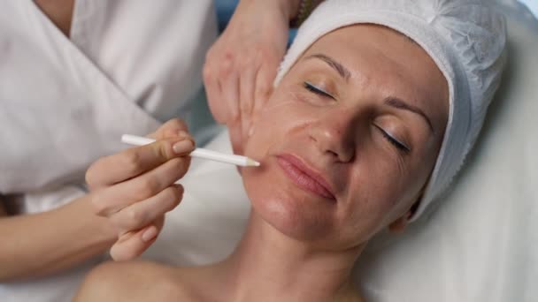 Un cosmetólogo dibuja con un marcador en la cara de los pacientes. Una mujer vino a una clínica de cosmetología para inyecciones de belleza y un lifting facial de la piel. Imágenes de alta calidad 4k - Metraje, vídeo
