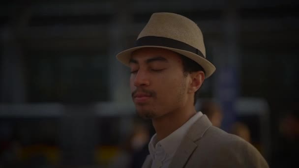 Divatos fiatal jóképű férfi kalapban és alkalmi ruhában a városban - Felvétel, videó