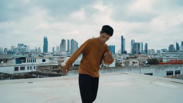 B-boy dança desempenho por dançarina de rua no telhado com scrapper céu, vista da cidade. Atraente asiático hipster mostrar passo energético. Dançarino de pausa praticar dança de rua. Desporto ao ar livre 2024. hiphop. - Filmagem, Vídeo