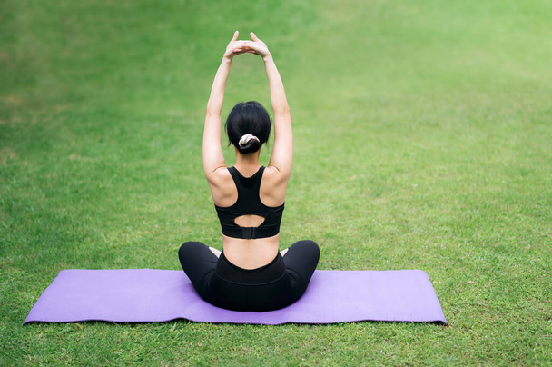 retrato ajuste joven mujer asiática en ropa deportiva rosa con estera de yoga. estirando los músculos en el parque. Mejorar la salud y la vitalidad a través de la práctica de yoga. Conéctese con la naturaleza para una serena - Foto, Imagen