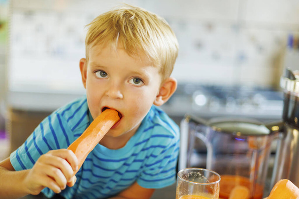 Маленький ребенок кусает свежую морковку - Фото, изображение
