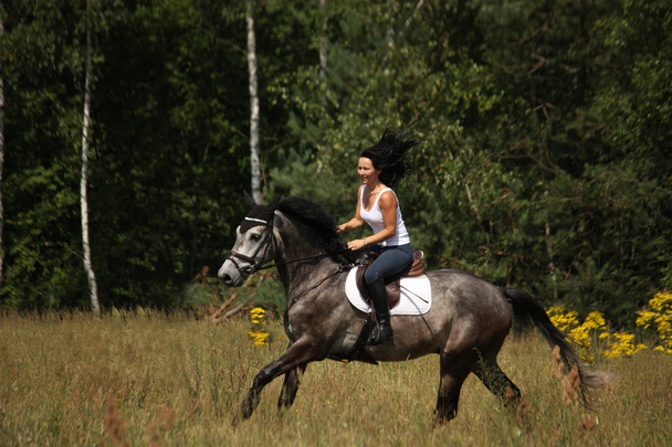 Красива жінка верхи на сірому коні в лісі
 - Фото, зображення