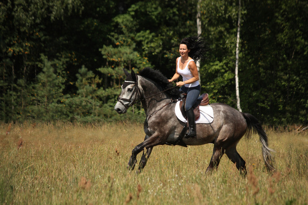 Hermosa mujer montando caballo gris en el bosque
 - Foto, imagen