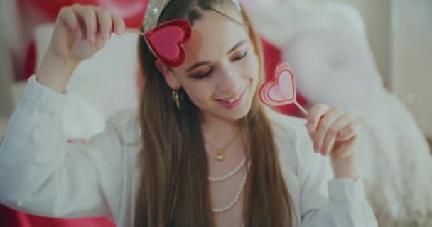 Ευτυχισμένη νεαρή γυναίκα που κρατά καραμέλες σε σχήμα καρδιάς κατά τη διάρκεια της ημέρας Galentines - Πλάνα, βίντεο