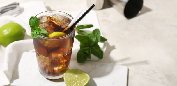 Glass of tasty Cuba Libre cocktail on light background with space for text - Foto, Bild