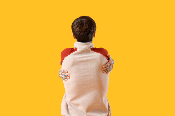 Jovem abraçando-se no fundo amarelo, visão traseira - Foto, Imagem