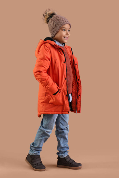 Netter afroamerikanischer Junge in warmer Kleidung auf braunem Hintergrund - Foto, Bild