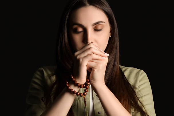黒い背景にビーズで祈る美しい女性,クローズアップ - 写真・画像