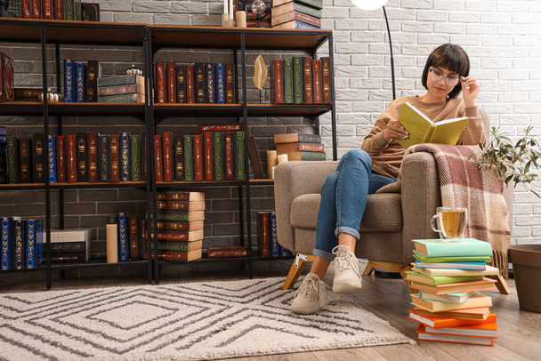 Mladá žena s brýlemi čtení knihy v knihovně - Fotografie, Obrázek