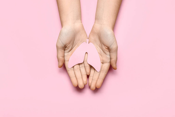 Kobiece ręce z papierowymi płucami na różowym tle - Zdjęcie, obraz