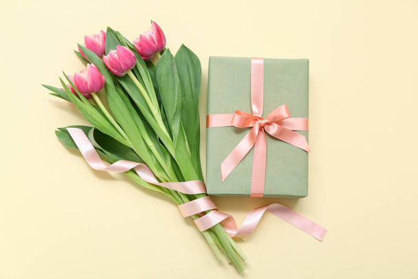 Caja de regalo y ramo de hermosos tulipanes sobre fondo amarillo. Día Internacional de la Mujer - Foto, imagen