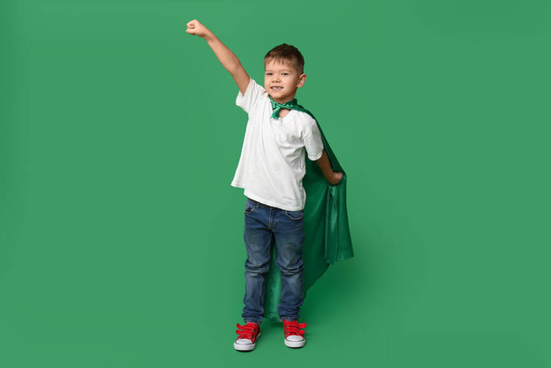 Милый маленький мальчик, одетый как супергерой на зеленом фоне - Фото, изображение