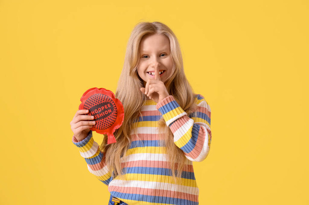 Vtipná holčička s polštářkem ukazujícím na žlutém pozadí gesto mlčení. Dubnová oslava Dne bláznů - Fotografie, Obrázek