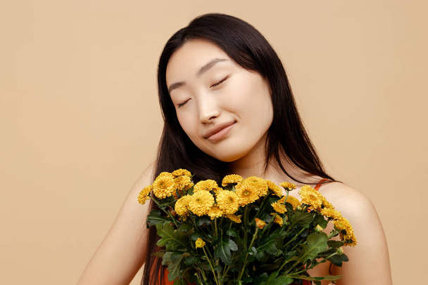 幸せな魅力的なアジアの女性,ベージュの背景,結婚式の日に隔離された美しい黄色い花の花束を保持するかわいい花嫁. 自然美,春の時間,国際女性デーコンセプト  - 写真・画像