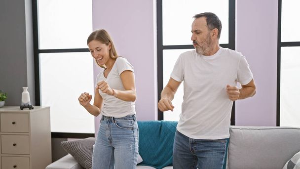 Confident father and beaming daughter dancing together, filling their home with laughter and joy, radiating positivity - Photo, Image