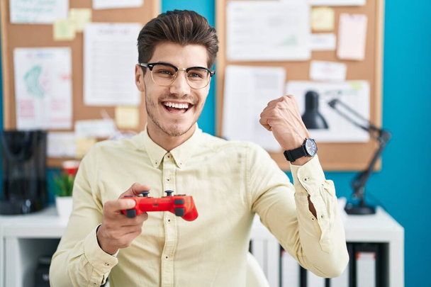 Mladý hispánec muž obchodní pracovník hraje videohry v kanceláři - Fotografie, Obrázek