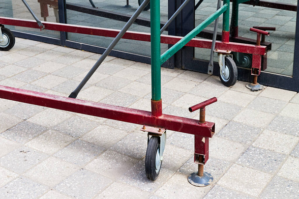 soporte de andamios sobre ruedas y gatos de tornillo instalados cerca del escaparate - Foto, imagen