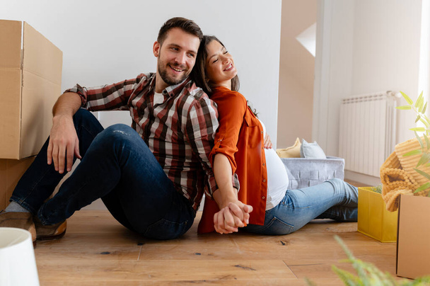 couple assis sur le sol avec des boîtes en carton à la maison déménageant dans une nouvelle maison  - Photo, image