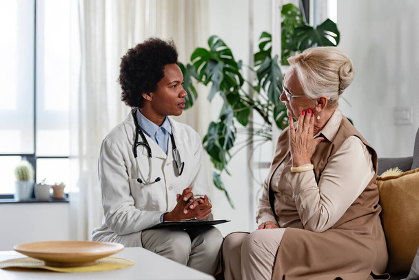 афроамериканська жінка-лікар розмовляє з пацієнтом старшої жінки - Фото, зображення