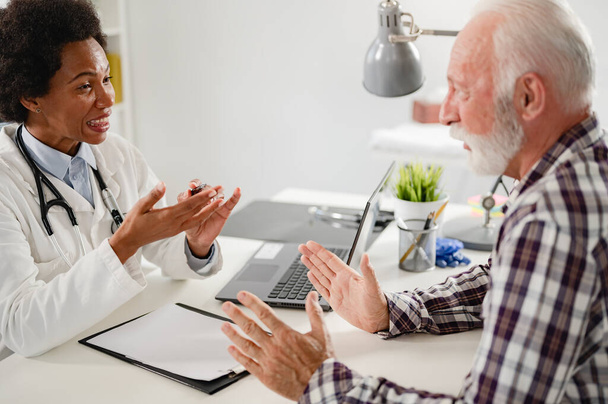 Arzt spricht mit Seniorin in Klinik - Foto, Bild