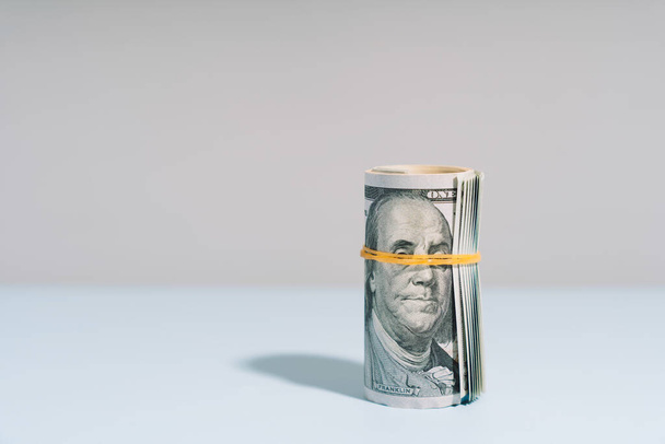 One hundred dollar bills rolled up on light background. High quality photo - Photo, Image