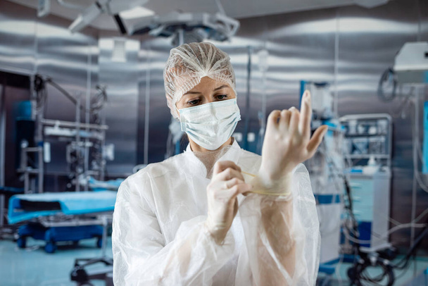 Ärztinnen tragen Laborkittel und legen bei Operationen sterile Handschuhe an. Krankenpfleger. Medizinisches Konzept - Foto, Bild