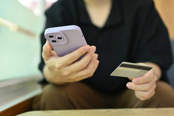 Чоловік використовує мобільний телефон і кредитну картку для банківських операцій і покупок онлайн. - Фото, зображення