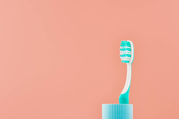 Cepillo de dientes manual sobre fondo rosa con espacio para copiar. Vista frontal desde ángulo bajo. - Foto, Imagen
