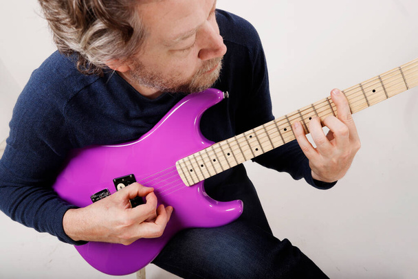 anonymous man practicing guitar sitting down white background - Photo, Image