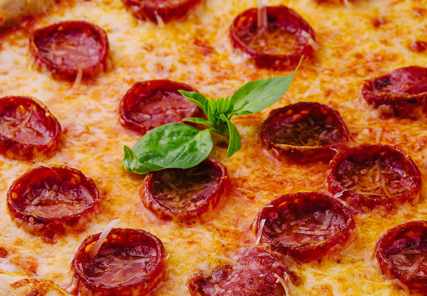 Pepperoni Pizza met Basilicum en Parmezaanse kaas close-up - Foto, afbeelding