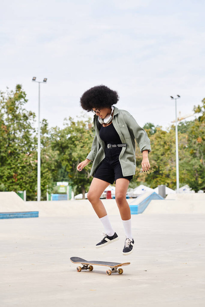 セメント表面のスケートパークでカーリーヘアスケートボードをしている若いアフリカ系アメリカ人女性. - 写真・画像