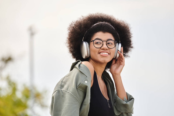 A stylish young woman enjoying music in her headphones while wearing a trendy jacket. - Photo, Image