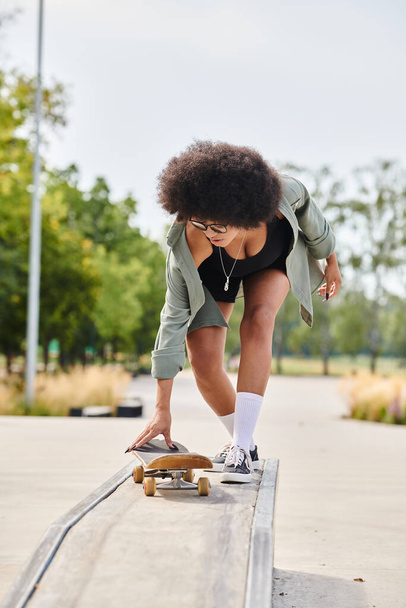 A young African American woman with curly hair confidently skateboarding down a metal rail at an outdoor skate park. - Photo, Image